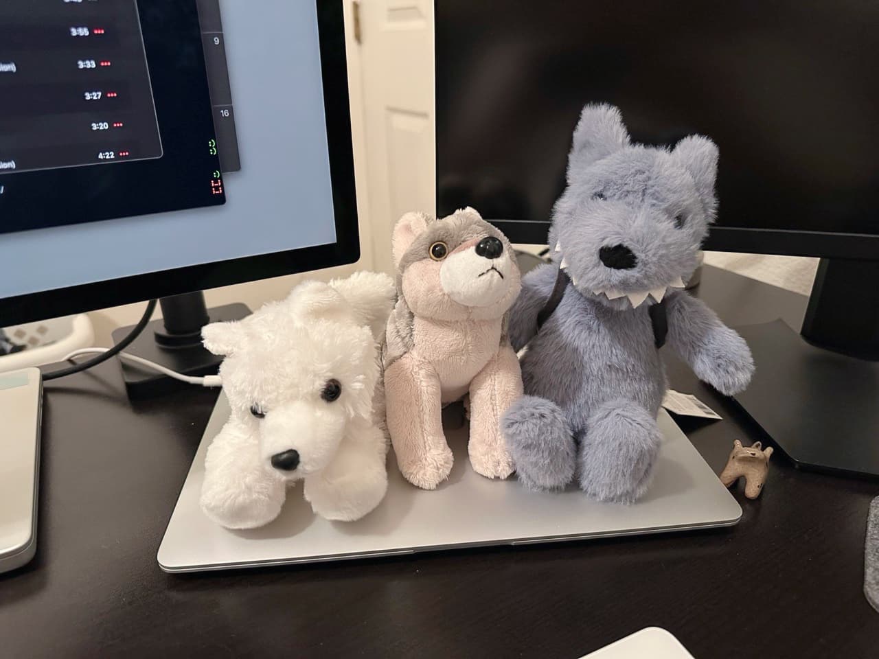 A photo of three stuffed animals placed on top of a MacBook Air, which is on my desk.